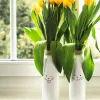 Two white vases decorated with bunny faces, filled with yellow tulips, sit on a windowsill. Náhled obrázku produktu