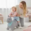 A mother is helping her baby ride on a gray inflatable pony toy in a living room. Anteprima dell’immagine prodotto