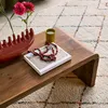 A wooden coffee table with decorative items on it, placed on a patterned rug. Produktbild-Vorschau