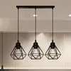 A close-up shot of a black pendant light fixture with three diamond-shaped metal shades hanging from a rectangular base. Produktbild-Vorschau