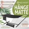 A black hammock with a stand, pillows, and a storage bag, set against a background with green leaves and text. Produktbild-Vorschau