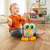 A young child is playing with a toy owl on the floor in a room with shelves in the background. Náhled obrázku produktu