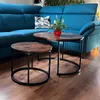 A living room scene with a blue sectional sofa and two nesting coffee tables. Produktbild-Vorschau