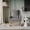 A cozy living room scene featuring a gray teddy plush rocking chair, a floor lamp, and decorative items. Produktbild-Vorschau