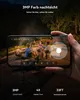 A hand holding a smartphone displaying a night vision security camera feed of people gathered around a fire pit outdoors. Produktbild-Vorschau