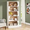 A modern white bookshelf filled with decorative items and books, placed in a living room setting next to a chair and a window with curtains. Produktbild-Vorschau