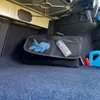 The image shows the interior of a car trunk with a black organizer bag containing blue gloves and a silver cylindrical object. A red flashlight and a blue container are also visible. Náhled obrázku produktu