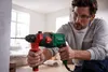 A man is using a drill to make a hole in a wall. Produktbild-Vorschau