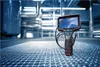 A Bosch inspection camera is placed on a metal grate floor in what appears to be an industrial setting with pipes and machinery in the background. Anteprima dell’immagine prodotto