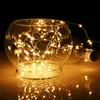 A close-up shot of a glass bowl filled with micro LED string lights, with a glass bottle in the background. Produktbild-Vorschau