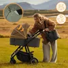 A woman with a baby stroller in a grassy field with mountains in the background. Produktbild-Vorschau