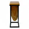 A side view of a C-frame side table with a teak wood top and a unique, curved teak wood insert. Voir les images du produit