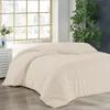 A bed with cream-colored bedding is shown in a room with a large window and a plant. Produktbild-Vorschau