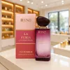 A perfume bottle and its box are displayed on a white surface in front of a blurred store background. Náhľad obrázku produktu