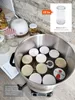A canning pot filled with lids and jars, with a diffuser and jars in the background. Podgląd zdjęcia produktu
