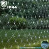 A net of white lights is draped over a garden setting with grass and bushes. Produktbild-Vorschau