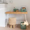 A desk with storage baskets, a lamp, a stool, and decorative lights. Anteprima dell’immagine prodotto