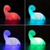 A collage of four images, each showing a different colored dinosaur-shaped LED lamp against a black background. Voir les images du produit