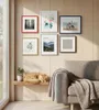A living room scene with framed pictures on the wall, a sofa with a blanket, and a cat sleeping on a shelf. Produktbild-Vorschau