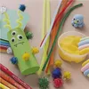 A collection of craft supplies for making a monster, including pipe cleaners, googly eyes, pom-poms, and modeling clay. Produktbild-Vorschau