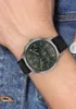 A person's wrist wearing a Tommy Hilfiger watch, with denim fabric in the background. Produktbild-Vorschau