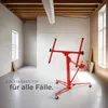 A red drywall lift is shown in an empty room with wooden ceiling beams and a large white air duct. Náhled obrázku produktu