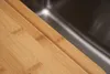 A close-up shot of a wooden cutting board next to a stainless steel sink. Produktbild-Vorschau
