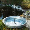 A solar-powered fountain kit is set up in a garden pond, with a solar panel visible. Produktbild-Vorschau