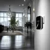 A wireless doorbell is mounted on a wall in a hallway, with musical notes emanating from it, suggesting it plays melodies. The hallway is elegantly decorated with a chandelier, large mirror, and ornate furniture. Náhľad obrázku produktu