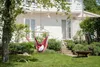 A backyard scene with a hammock chair hanging from a tree, a small table with drinks, and a fire pit. Anteprima dell’immagine prodotto