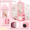 A pink children's jewelry cabinet with a mirror, displayed in a room with pink and white heart-patterned wallpaper. Various close-up shots highlight features like heart-shaped cutouts, the mirror's reflection, a recessed handle, a magnetic closure, and ant Podgląd zdjęcia produktu