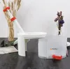 A cherry pitter and collection bin are displayed on a dark gray surface, with dried wheat stalks and a vase of dried flowers in the background. Produktbild-Vorschau