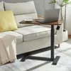 A laptop table is placed next to a sofa, with a laptop and a cup of coffee on it. Náhľad obrázku produktu