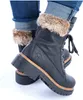 A close-up shot of a pair of black lace-up boots with fur trim, worn with cuffed jeans. Anteprima dell’immagine prodotto