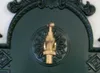A close-up of a dark green wall-mounted fountain with a brass faucet. Produktbild-Vorschau