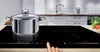 A pot is placed on a modern induction cooktop in a kitchen setting. Voir les images du produit