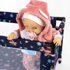 A doll is placed in a travel crib with a floral pattern. Produktbild-Vorschau