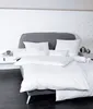 A neatly made bed with white bedding and a grey headboard. Produktbild-Vorschau