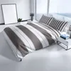 A neatly made bed with striped bedding in a modern room with large windows. Produktbild-Vorschau