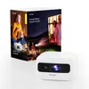 A product box for a mini projector is shown next to the projector itself. The box features lifestyle images of people using the projector outdoors and indoors. Produktbild-Vorschau