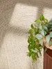 A close-up view of a braided jute rug with a potted plant in the foreground. Anteprima dell’immagine prodotto