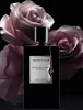 A black bottle of Van Cleef & Arpels Moonlight Rose perfume is displayed in front of two large, pale pink roses against a black background. Voir les images du produit