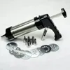 A cookie press with various attachments and discs is laid out on a white and gray surface. Podgląd zdjęcia produktu