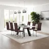 A modern dining room with a white table and chairs, set on a rug with a large plant and artwork in the background. Náhled obrázku produktu