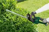 A person is using a hedge trimmer to trim a bush in a garden. Produktbild-Vorschau