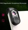 A smartphone microscope clip-on lens attached to a smartphone, with a dark green, leaf-patterned background. Produktbild-Vorschau