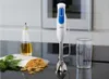 A Braun hand blender is shown on a kitchen counter next to a bottle of oil, some herbs, and pasta. Produktbild-Vorschau
