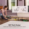A woman is demonstrating the flexibility of a cordless vacuum cleaner by showing how it can reach under furniture. Produktbild-Vorschau