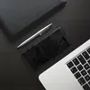 A flat lay of a black phone case, a silver pen, and a laptop on a dark wooden surface. Produktbild-Vorschau