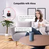 A woman is sitting on a couch in a living room, holding a mug, and interacting with a smart speaker. A ThermoPro device is shown on the wall in a close-up inset, and text bubbles indicate a voice command and response. Produktbild-Vorschau